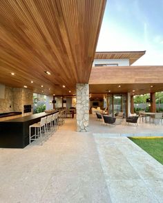 an outdoor kitchen and living room area with stone walls, wood ceilinging and large windows