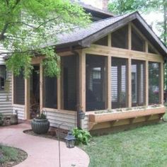 a small house sitting in the middle of a lush green yard next to a tree