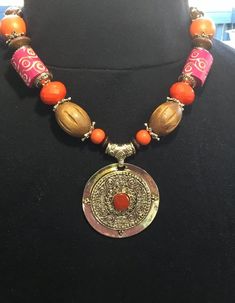 Necklace by Erica Lyons is 12 inches long and adorned with multiple materials; pendant, beads, spacers, chain, and lobster clasp.  Colors include; red, orange, brown, and gold.  Pendant is 2-3/8 inches in diameter with a red stone inlaid.  The necklace weighs 3.5 ounces. Red Stone, Orange Brown, Gold Pendant, Pendant Necklaces, Lobster Clasp, Favorite Jewelry, Necklace Etsy, Jewelry Necklace Pendant, Beauty Book