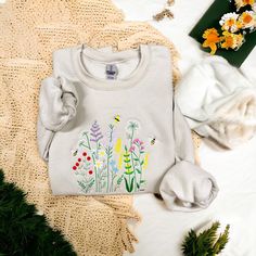 This cozy unisex sweatshirt is embroidered with wildflowers. The perfect fall sweater!  All sweatshirts are Gildan 18000 Unisex sweatshirts. They are a cozy soft fabric made from a soft cotton/poly blend with no itchy side seams, this is sure to become a staple. Sizing details:  * All sweatshirts are unisex sizing, please refer to the size chart in the listing photographs to determine your size.  * If you are not sure what size to order, you can measure a sweatshirt you already own to see what s Summer Floral Embroidered Crew Neck T-shirt, Spring Floral Embroidery Sweatshirt, Embroidered Flower Sweatshirt, Spring Cottagecore Crew Neck T-shirt, Spring Crew Neck T-shirt With Butterfly Embroidery, Spring Butterfly Embroidered Crew Neck T-shirt, Flower Crew, T Shirt Flowers, Embroidered Hoodie