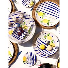 plates and bowls with lemons on them are laid out in rows, along with utensils