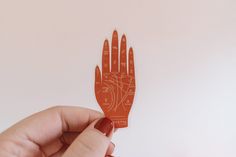 a hand that is holding an orange piece of paper with writing on it and compasses in the palm