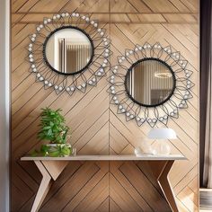 two mirrors on the wall above a table with a vase and plant in front of it