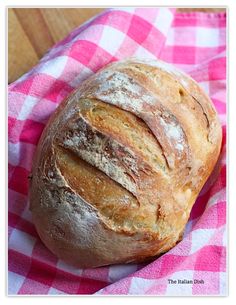 a loaf of bread sitting on top of a pink and white checkered cloth