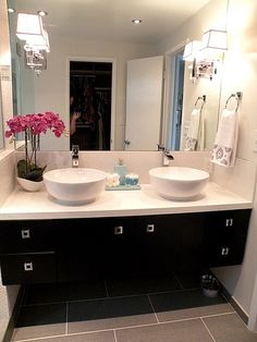 two white bowls are sitting on the counter in front of a large mirror and sink