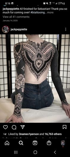 the back of a woman with tattoos on her arms and chest, sitting in front of a window