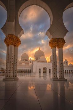 the sun is setting in front of an ornate white building with arches and pillars on either side