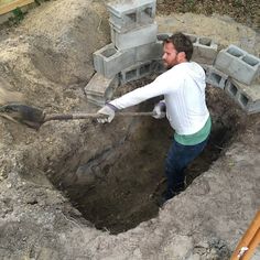 a man with a shovel digging into a hole in the ground that is filled with cement