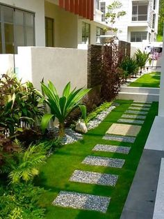 a garden with grass, rocks and plants in front of a building on the sidewalk