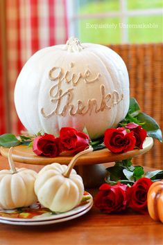 a white pumpkin sitting on top of a wooden table next to red roses and other decorations