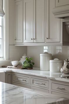 a kitchen with white cabinets and marble counter tops