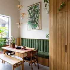 a dining room table and bench in front of a window with potted plants on it