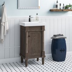 a white sink sitting next to a blue trash can in a bathroom under a mirror