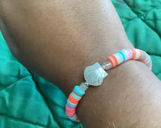 a close up of a person wearing a bracelet with seashells on it's side