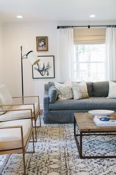 the living room is decorated in white and neutrals, including an antler's head