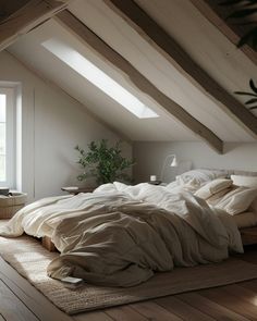 an attic bedroom with wooden floors and white walls, has a large bed that is covered in beige linens