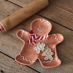 a cookie shaped like a ginger on a wooden table next to a rolling pin and doughnut