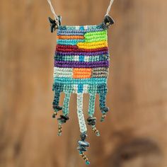 a multicolored beaded necklace hanging from a string on a wooden background with beads