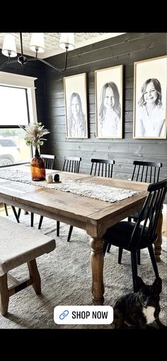 a dog laying on the floor in front of a dining room table with chairs and pictures above it