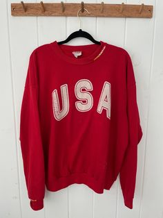 "Vintage 90's USA Crewneck Sweatshirt with hand stitched embroidery on collar and sleeve cuff.  Vintage Gear. Unisex Adult Sizing **Vintage sizing varies, please consult measurements.  Other details: Brand: Santee by Puma Made in: USA Material: Cotton & Polyester Colour: Red Size: XL Style: Crewneck Sweatshirts Pattern: Graphic  **Measurements*  Chest (Pit to pit): 24.5\" Length (Neck to hem): 26\" Sleeve (Pit to cuff): 23\" * All Measurements done on flat laying garments Composition: 50% cotton, 50% polyester. No holes. Bleach stain - see pictures.  Please note, each item is preowned. There is a story/tale behind each stain, hole, pull etc. Perfectly imperfect, however, please consult pictures closely and read all descriptions. All sales FINAL.  Check us out on Instagram for vintage drops Vintage Long Sleeve Sweatshirt With Letter Embroidery, Vintage Relaxed Fit Top With Embroidered Logo, Vintage Red Tops With Ribbed Cuffs, Vintage Red Top With Ribbed Cuffs, Vintage Long Sleeve Tops With Letter Embroidery, Vintage Letter Embroidery Tops For Streetwear, Vintage Long Sleeve Tops With Embroidered Text, Vintage Crew Sweatshirt With Embroidery, Vintage Embroidered Crew Sweatshirt