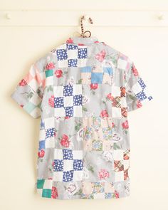 a shirt hanging up on a wall with flowers and polka dots in the front pocket