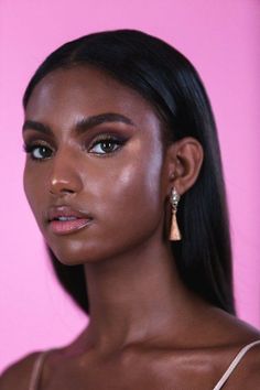 a woman with long black hair wearing gold earrings and a white top is looking at the camera