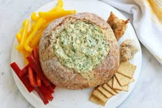 a white plate topped with a sandwich next to crackers and veggie chips