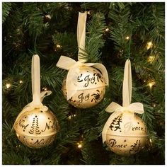 three ornaments hanging from a christmas tree decorated with gold and white ribbons, saying joy to the world