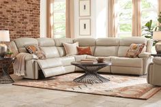 a living room filled with lots of furniture in front of a brick wall and windows