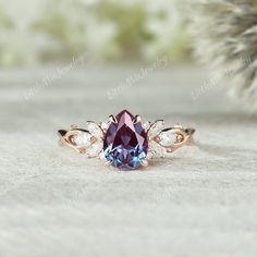 a pink and blue ring sitting on top of a white table next to a pine tree