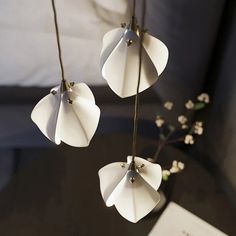 three white paper flowers hanging from a string on top of a table next to a book