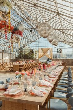 a long table set up for an event in a glass walled room with chandeliers