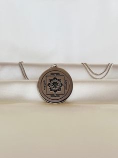 a white satin bag with a medallion on the front and chain hanging from it's side