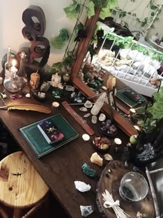 a wooden table topped with lots of clutter next to a mirror and potted plants