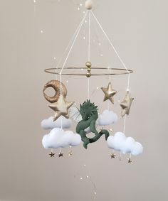 a mobile with stars and a green dragon hanging from it's sides in the sky