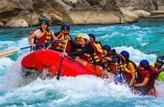 a group of people riding on the back of a red raft down a rapid river