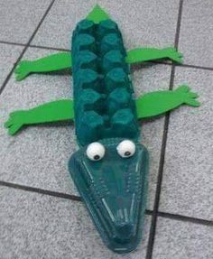 an egg carton shaped like a crocodile laying on the ground with eyes and legs