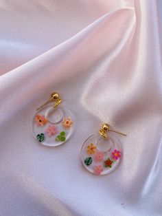 These cute resin earrings come with mini flowers and leaves. They have a gold ball stud.  Sizing: Circle is about 1 inch. Resin Flower Charm Drop Earrings, Flower Charm Resin Earrings, Resin Earrings With Flower Charm, Summer Gold Resin Earrings, Resin Flower Earrings With Flower Charm, Trendy 3d Flower Earrings, Trendy Round Flower Earrings As Gift, Trendy Round Flower Earrings For Gift, Gold Round Flower Earrings In Resin