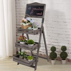 a welcome to home sign with potted plants on it and a chalkboard in the background