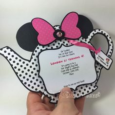 someone is holding up a minnie mouse shaped card with a pink bow on it's head