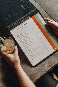 a person sitting at a table with a drink and menu in front of them on a clipboard