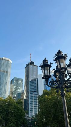 there are many street lights in the city with tall buildings behind them and trees on both sides