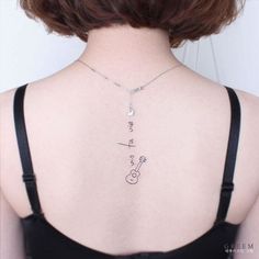 the back of a woman's neck with a small tattoo on her left shoulder