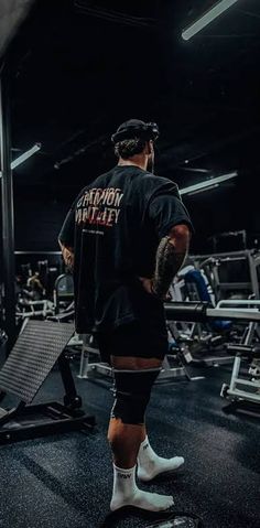 a man standing in the middle of a gym with his back turned to the camera