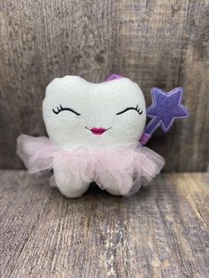 a tooth fairy stuffed animal sitting on top of a wooden table next to a purple star