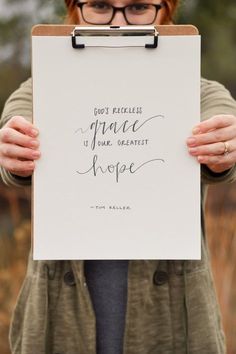 a woman holding up a piece of paper with the words grace and hope written on it