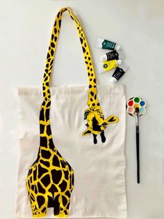 a giraffe painted on a canvas bag next to paintbrushes and markers