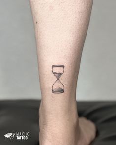 a person with a tattoo on their leg that has an hourglass in the sand