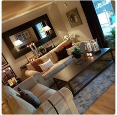 a living room filled with lots of furniture next to a large window covered in candles