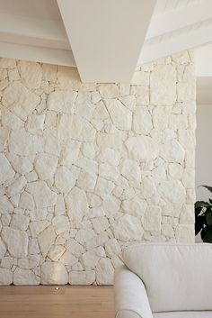 a white couch sitting in front of a stone wall